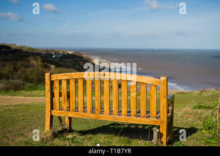 Holz- erinnerungsbank auf Overstrand Klippe mit Blick auf die Küste von Norfolk und die erodierten Felsen Stockfoto