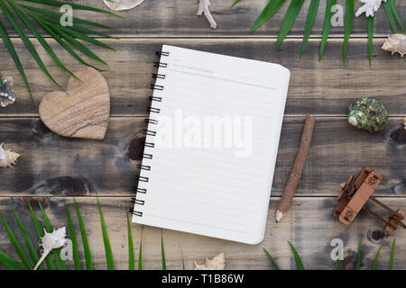 Flach leere Notepad mit Herzform rock, Muscheln, Palmenblättern und Flugzeug Modell. Urlaub tropical beach Reisen Urlaub Konzept. Ansicht von oben mit c Stockfoto