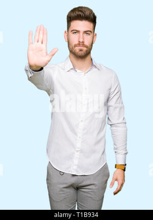 Junge gut aussehender Geschäftsmann tun halt Singen mit der Hand. Warnung Ausdruck mit Negativen und schweren Geste auf dem Gesicht. Stockfoto