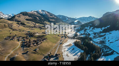 Atemberaubende Luftaufnahmen über der a Swiss Alpine Stadt und Talkessel, umgeben von schneebedeckten hohen Berggipfeln und die Berge. Stockfoto