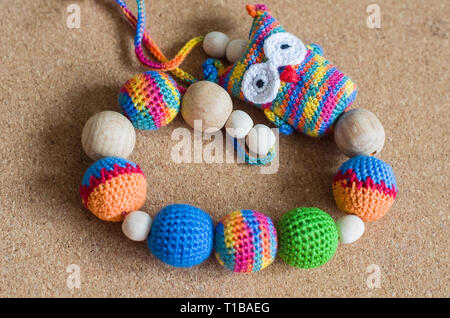 Halskette aus Perlen gestrickt und Spielzeug für das Baby im Tragetuch sitzen. Aus Perlen. Sling Halskette. Eule aus Baumwolle melange farbigen Garnen. Stockfoto