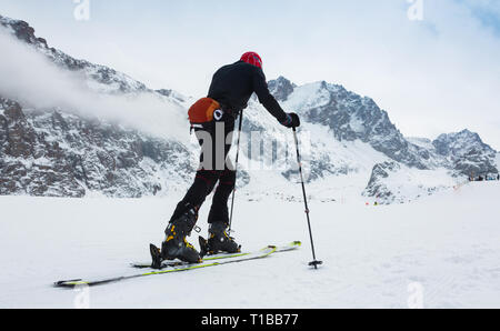 Bergsteiger backcountry Ski Wandern entlang einer verschneiten Bergrücken mit Skiern in den Rucksack. Im Hintergrund blaue Himmel und die glänzende Sonne und Zebru und Ortler im Süden Stockfoto