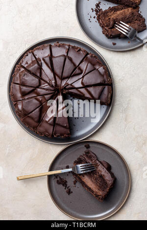 Top view Konzept von zwei Stücke Schokolade Kuchen mit den ganzen Kuchen auf grauen Platten an hellen Hintergrund. Konzept der Holiday Dessert Stockfoto