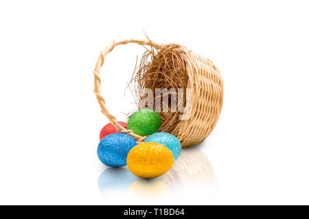 Bunte Ostereier aus Nest auf Holz- korb über weißem Hintergrund verschüttet. Frohe Ostern Stockfoto