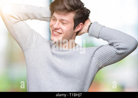 Jungen gutaussehenden Mann tragen winter Pullover über isolierte Hintergrund Entspannung und Stretching mit Armen und Händen hinter dem Kopf und Hals und lächelte glücklich Stockfoto