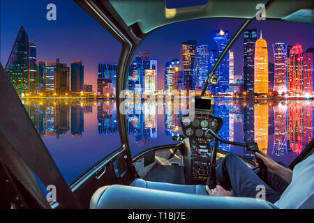 Helicopter Cockpit Innenraum über Doha Bucht Hafen mit malerischen Skyline am Blauen Stunde reflektieren fliegen. Nachtleben in Doha am Wasser Meer. Katar Stockfoto