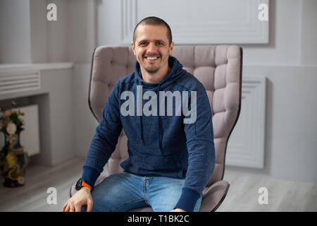 Mann in dunkelblauer Hoodie lächelnd und Suchen in der Kamera Stockfoto