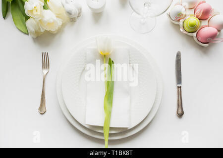 Ostern Abendessen. Tabelle mit White Tulip, bunte Eier auf weißer Tisch. Ansicht von oben. Platz für Text. Stockfoto