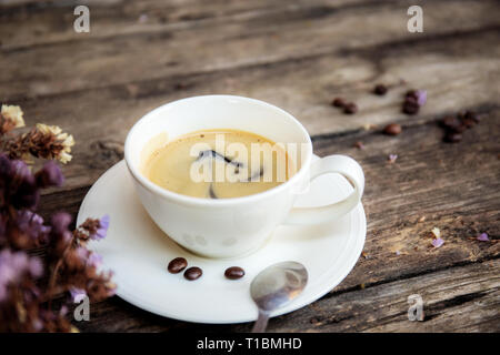 Kaffeetasse und trockenen Blume auf Holz- Hintergrund. Stockfoto