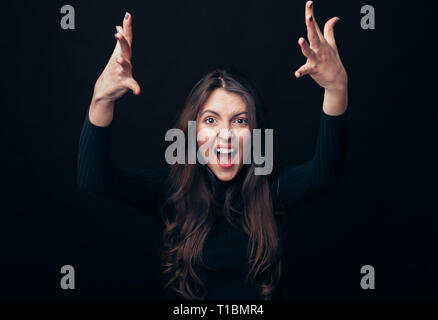 Schreien emotionale wütende Frau mit Waffen bis auf schwarzem Hintergrund isoliert. Negative Emotionen, Hass, Wut oder Stress Konzept Stockfoto