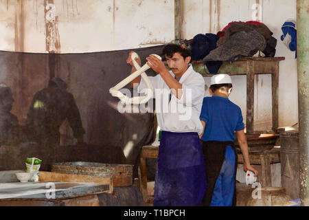 Junger uigurischer Mann, der handgezogene Nudeln herstellte, Kashgar-Sonntagsmarkt, Kashgar, Xinjiang Autonome Region, China. Stockfoto
