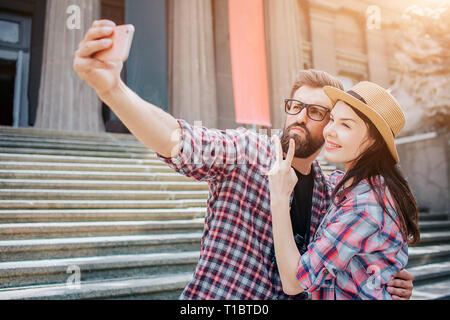 Junger Mann und Frau stehen zusammen und nimmt selfie. Er hält der Kamera in der Hand. Sie stellen. Die Menschen auf der Treppe. Stockfoto