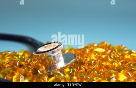 Fischöl Kapseln mit Stethoskop auf blauem Hintergrund. Gesunde omega-3 und Stethoskop. Stockfoto