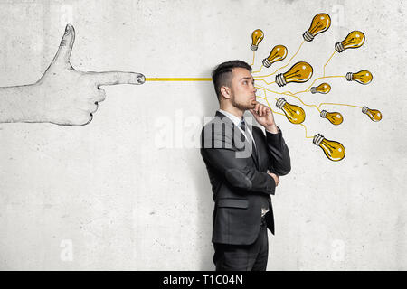 Geschäftsmann in halbe Umdrehung, Hand am Kinn, in der Nähe von Wall mit handgezeichneten finger Gewehr schießen Bündel gelb electirc Glühlampen ihn an. Stockfoto