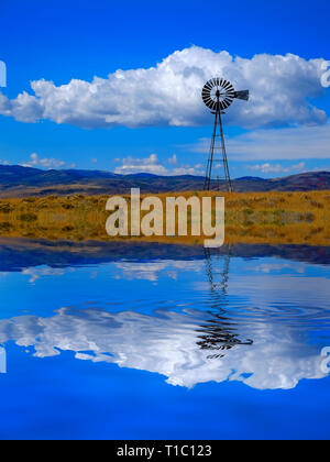 Windmühle auf einem Hügel in der Landschaft des ländlichen Amerika mit Himmel und Wolken Reflexion im Wasser wie ein lke oder Teich spiegeln Spiegel Stockfoto