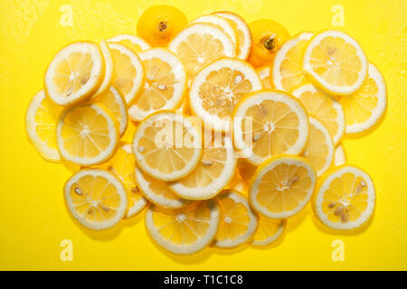 In Scheiben geschnittene Zitronen auf gelbem Hintergrund. Stockfoto
