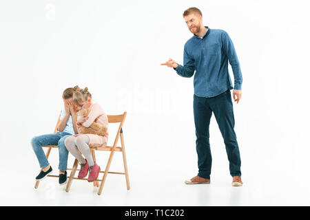 Wütende Vater seinen Sohn und Tochter zu Hause Schelte. Studio shot der emotionalen Familie. Menschliche Emotionen, Kindheit, Probleme, Konflikte, das häusliche Leben, Beziehung Konzept Stockfoto