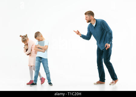 Wütende Vater seinen Sohn und Tochter zu Hause Schelte. Studio shot der emotionalen Familie. Menschliche Emotionen, Kindheit, Probleme, Konflikte, das häusliche Leben, Beziehung Konzept Stockfoto