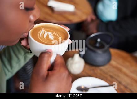 Frau sitzt in einem Café Tisch trinken ihren Cappuccino Stockfoto