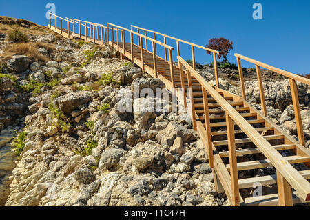 Hölzerne Treppe an der felsigen Küste entfernt. Und sonniger Sommertag im Mittelmeer statt. Treppen zum Himmel. Stockfoto