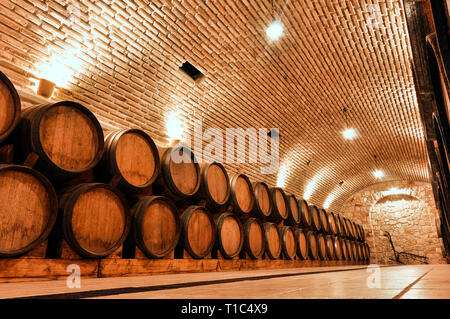 Weinfässer im alten Keller eines Weinguts. Weinkeller Der Weinkeller mit gemauerten Wänden. Stockfoto