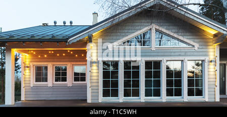 Fassade des grossen schönen Holzhaus mit Panoramafenstern. Modische Beleuchtung an der Fassade. Lettland Stockfoto