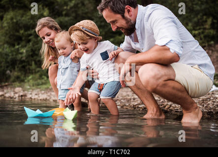 Junge Familie mit 2 Kleinkind Kinder draußen am Fluss im Sommer spielen. Stockfoto