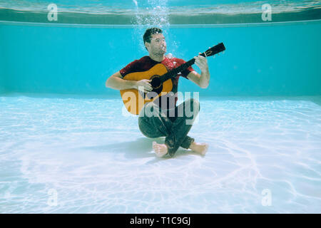 Junge Mann spielt Musik mit Gitarre und Gesang Song Unterwasser Stockfoto