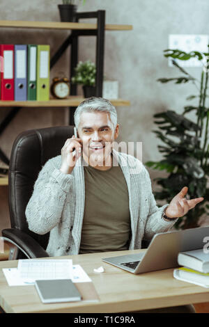 Schön positiver Mann spricht über die Arbeit am Telefon Stockfoto