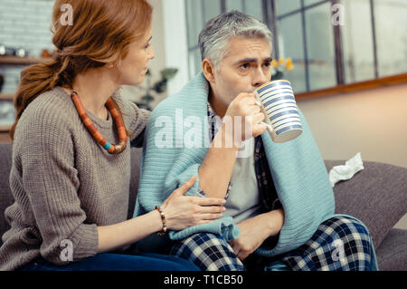 Schön kranke Mann trinken heißen Tee mit Zitrone Stockfoto