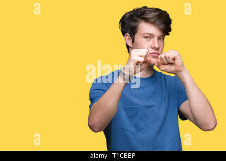 Jungen gutaussehenden Mann trägt blaue T-Shirt über isolierte Hintergrund Stanzen Faust zu kämpfen, aggressiv und wütend Angriff, Bedrohung und Gewalt Stockfoto