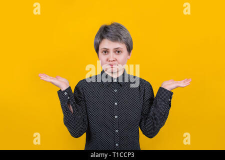 Clueless verwirrte Frau mit weit geöffneten Augen zu Zögern in zuckte mit den Schultern Unsicherheit auszudrücken. Mimik, leben Wahrnehmung eine Stockfoto