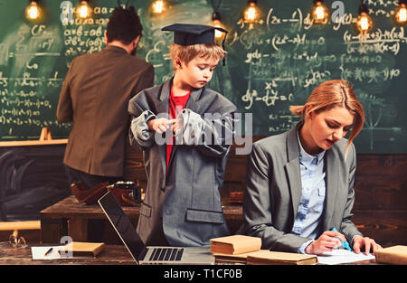 Kind und Schule Konzept. Sohn Vorschulkind lehrt Mutter zu schreiben, Vater ziehen am Schwarzen Brett. Kid Wachstum und Entwicklung Stockfoto