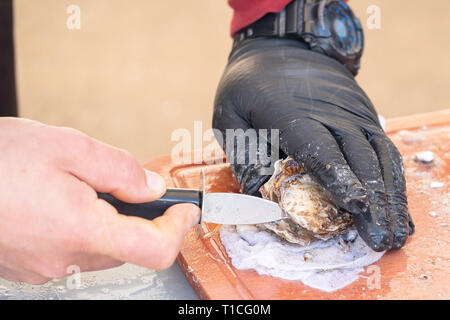 Mann öffnen Auster auf dem Markt. Nähe zu sehen. Stockfoto