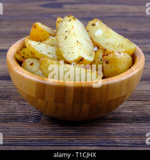 Gebratene Kartoffeln mit Provence Kräuter und Salz in der Schüssel auf Holz- Hintergrund. Nähe zu sehen. Stockfoto