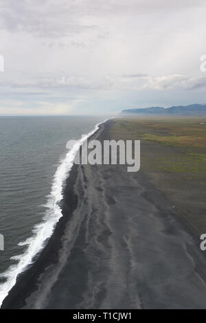 Der schwarze Sandstrand mit typisch isländischen Berglandschaften Luftaufnahme Stockfoto