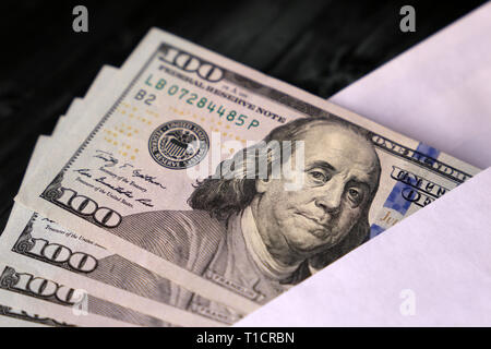 US-Dollar Scheine in der Umschlag auf dem hölzernen Tisch. Einkommen, Bonus oder Bestechung Konzept Stockfoto