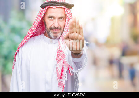 Senior arabischen Mann mit kufiya über isolierte Hintergrund tun halt Singen mit der Hand. Warnung Ausdruck mit Negativen und schweren Geste Stockfoto