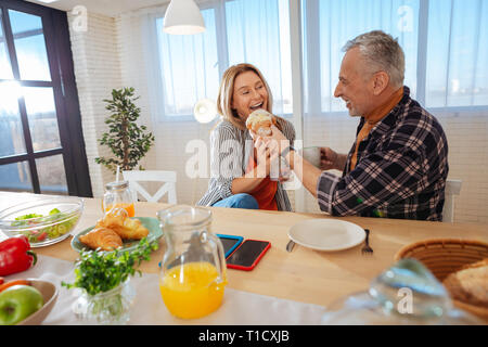 Paar teilen große leckere Croissant am Morgen Stockfoto