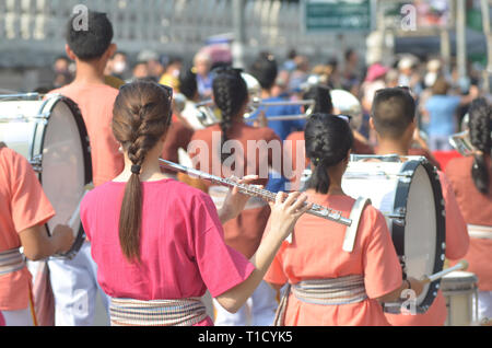 Junge Mädchen tragen traditionelle thailändische Anzug spielen Flöte für Show in marching band vorgeführt, auf der Straße mit unscharfen Hintergrund, Frau Flötenspieler in Ma voll Stockfoto