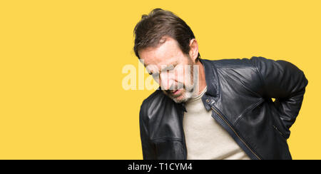 Mittleres Alter stattlicher Mann mit schwarzen Lederjacke leiden an Rückenschmerzen, Berühren mit der Hand zurück, Muskelschmerzen Stockfoto