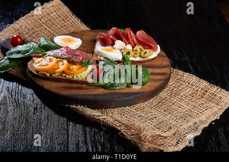 Schinken und Käse Sandwich auf geröstetem Toastbrot auf einer hölzernen Hintergrund mit Handwerk Papier, frische reife Gemüse Stockfoto