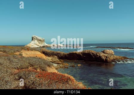 Mit Blick auf Felder, Klippen, Felsformationen und das blaue Meer unter strahlend blauem Himmel. Stockfoto