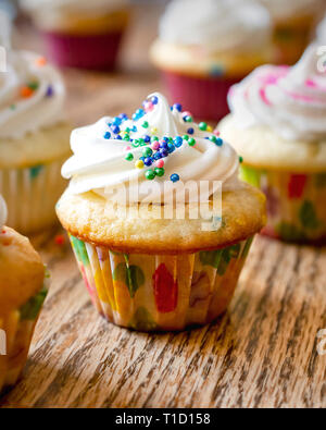 Nahaufnahme eines Mini Cupcake mit Zuckerguss und Pastell Streuseln. Stockfoto