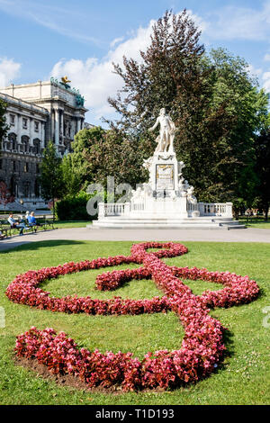 Das Mozart Denkmal im Burggarten, Innere Stadt, Wien, Österreich, mit einem Violinschlüssel aus begonien Blumen. Stockfoto