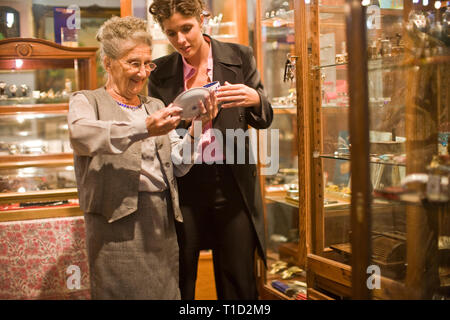 Lächelnd älteren Erwachsenen Frau Antique Shopping mit einem mittlerem - Erwachsene Business woman in einem Laden. Stockfoto