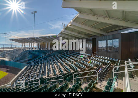 Sunlit tiered Sitze und die Zimmer in einem Stadion. Tiered Sitze an einem Stadion unter blauem Himmel und Sonne. Zimmer mit Zahlen und reflektierendem Glas Windows c Stockfoto