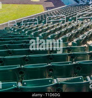 Ebenen der grünen Sitze für die Zuschauer in einem Stadion. Ebenen der grünen Sitze für Zuschauer und grünen Rasen im Stadion an einem sonnigen Tag. Getränkehalter kann eine Stockfoto