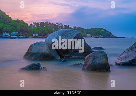 Vulkanischen Felsen und das Karibische Meer entlang dem Strand von Tayrona Nationalpark mit dem tropischen Regenwald im Hintergrund, Santa Marta, Kolumbien. Stockfoto