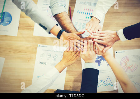 Multi-Ethnic Gruppe von Geschäftsleuten Hände zusammen setzen auf Schreibtisch mit voller Analysen-Business Einheit und Mitarbeiter brainstorming Konzept Stockfoto